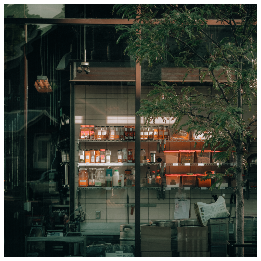 A restaurant kitchen bathed in sunset light, showcasing colorful ingredient bottles by the window"