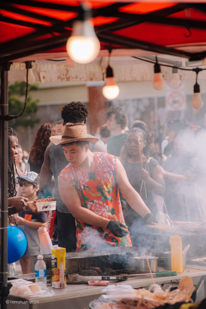 Another vendor skillfully grilling squid at his food stall, dressed in vibrant Chinese-patterned attire