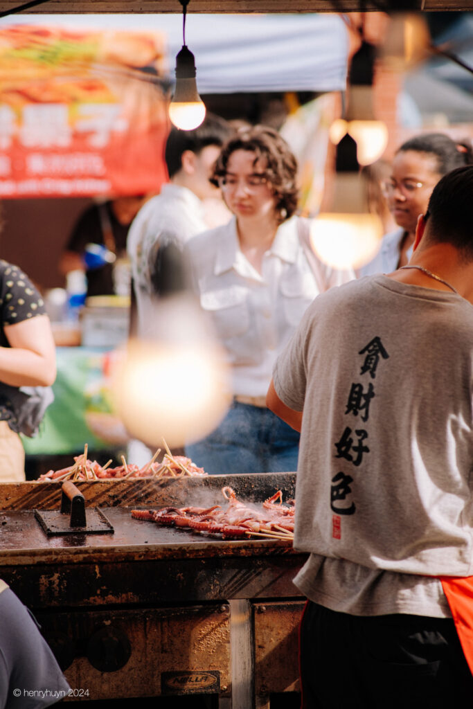 A young man expertly grilling squid at his food stall.