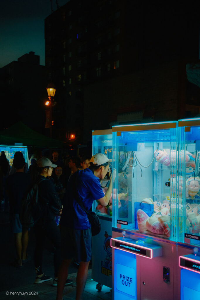 A photographer focuses intently, capturing the stuffed toys hanging in the claw machine.